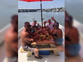 A lively group enjoys a crab feast on a boat, showcasing the perfect blend of family fun and delicious seafood in a picturesque setting.