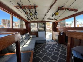 Interior view of a spacious boat cabin featuring comfortable seating and fishing gear, perfect for relaxing or preparing for a day of fishing.