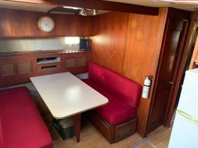 Interior view of a cozy boat cabin featuring red seating and a dining table, perfect for relaxing and enjoying meals while on the water.