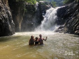 A group of friends enjoys a refreshing swim in a river beneath a stunning waterfall, capturing the essence of adventure and natural beauty.
