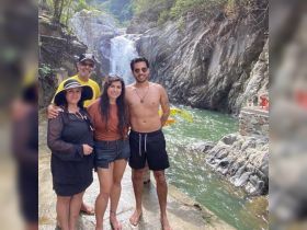 A cheerful group poses in front of a stunning waterfall, capturing a memorable moment in nature — perfect for family adventures and outdoor explorations.