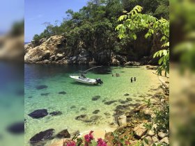 A picturesque beach scene featuring a group enjoying the clear waters, with a boat anchored nearby — perfect for a day of fun and relaxation in nature.