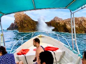 A group of friends enjoys an exhilarating boat ride near stunning rock formations, capturing the thrill of ocean adventures.