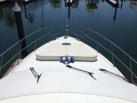 A clear view of the front deck of a yacht, showcasing its sleek design and tranquil marina setting — perfect for luxury boating experiences.