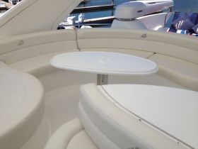 A stylish interior seating area of a luxury boat, featuring plush white cushions and a sleek table, perfect for relaxing or dining while on the water.