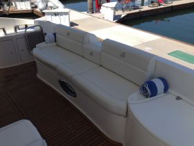 A spacious and stylish seating area inside a boat, featuring comfortable white cushions and neatly rolled towels, perfect for relaxing on the water.