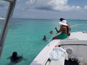 A lively group enjoys a refreshing swim in the turquoise waters while relaxing on the boat — perfect for a fun day out on the water.