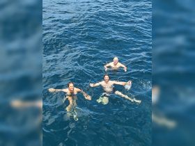 A joyful group of three swims in the clear blue waters, capturing the essence of fun and adventure during their boating experience.