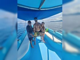 A cheerful group aboard a boat enjoys a delicious spread of food, perfect for a fun day on the water. The vibrant blue setting enhances the festive atmosphere.