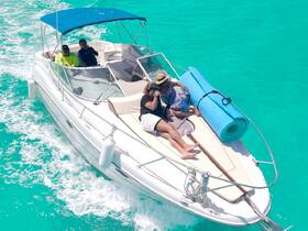 A lively group enjoys a sunny day on a boat, surrounded by stunning turquoise waters — perfect for fun and relaxation on the water.