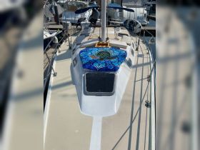 A view of the helm area on a sailboat, featuring a vibrant turtle-patterned blanket and crew members preparing for departure. Ideal for showcasing boat interiors and preparations for sailing.