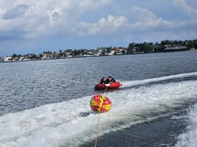 Two friends enjoy an exhilarating tubing ride on the water, showcasing the thrill of on-water activities and summer fun.