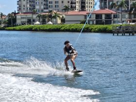 A thrilling moment captured as a wakeboarder glides across the water, showcasing the excitement of water sports in a vibrant setting.