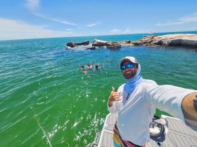 A joyful moment captured as a group enjoys snorkeling in the ocean, with rocky formations in the background — perfect for adventure seekers and marine exploration.