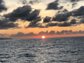 A stunning sunset over the ocean, capturing the vibrant colors of the sky as the sun dips below the horizon — perfect for serene evening boat rides.