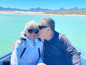 A couple shares a tender moment on a boat, surrounded by stunning turquoise waters and a picturesque landscape — perfect for romantic getaways or special celebrations.