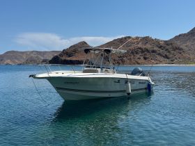 A sleek speedboat anchored in calm waters, surrounded by stunning rocky landscapes — perfect for a day of adventure on the water.