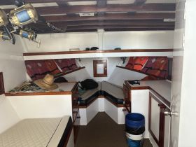Interior view of a boat cabin featuring seating areas, fishing gear, and storage, ideal for relaxing and preparing for fishing trips.