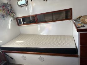 Interior view of a boat cabin featuring a comfortable seating area with a mattress, ideal for relaxation during trips on the water.