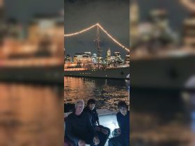 A group enjoys a nighttime boat ride with a stunning city skyline in the background, perfect for memorable celebrations and scenic views.
