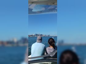 A couple enjoys a scenic view of the city skyline from their boat, capturing the essence of a perfect day on the water.