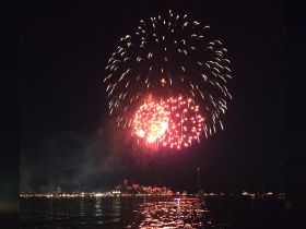 A stunning display of fireworks lights up the night sky over the water, creating a festive atmosphere perfect for celebrations and events.