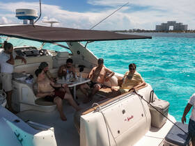 A lively group enjoys drinks and conversation aboard a yacht, surrounded by stunning turquoise waters — perfect for a day of celebration on the water.