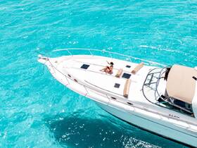 Aerial view of a couple enjoying the sun on the deck of a luxurious yacht, surrounded by stunning turquoise waters — perfect for a relaxing day on the water.