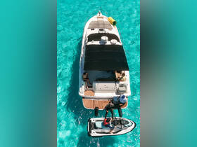 Aerial view of a group enjoying water activities on a yacht, with a jet ski being launched — perfect for adventure seekers on the open water.