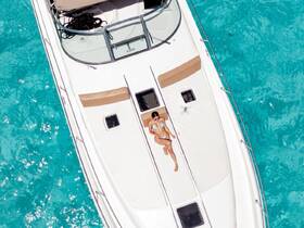 Aerial view of a woman sunbathing on the deck of a boat, surrounded by stunning turquoise waters — an ideal scene for relaxation and summer adventures.