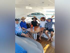 A lively group of friends enjoys their time aboard a boat, showcasing a fun atmosphere with colorful hats and drinks, perfect for a memorable day on the water.
