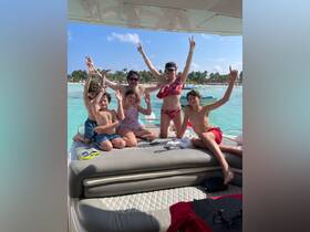 A joyful family poses on the deck of a boat, celebrating their day on the water with smiles and peace signs — perfect for family outings and summer adventures.