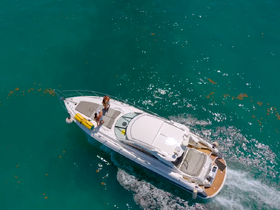 Aerial view of a boat cruising through clear turquoise waters, with guests enjoying the ride — perfect for adventure seekers and water enthusiasts.