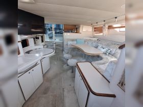 Interior view of a spacious boat cabin featuring comfortable seating and a dining area, perfect for relaxing and enjoying meals while on the water.