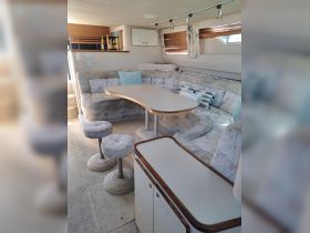A cozy interior view of a boat's lounge area featuring comfortable seating and a dining table, perfect for relaxing and socializing while on the water.