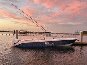 A stunning speedboat named 'Sea Runner' docked at sunset, showcasing its sleek design against a colorful sky — perfect for fishing or leisure outings.