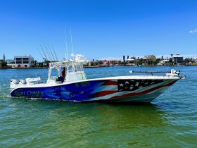 A striking speedboat named 'Skirt Chaser' navigates through clear waters, showcasing its vibrant design and fishing gear — perfect for charter adventures.