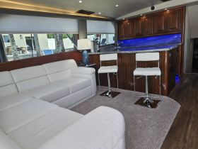 A stylish interior view of a boat's lounge area featuring a spacious white sectional sofa and modern bar stools, perfect for relaxing and entertaining on the water.