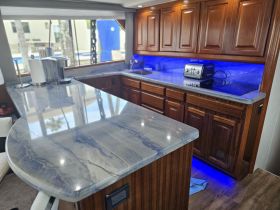 A beautifully designed boat interior featuring a modern kitchen area with sleek countertops and ambient lighting, perfect for onboard dining and entertaining.