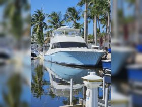 A stunning blue yacht docked in a serene marina, surrounded by lush palm trees, reflecting beautifully in the calm waters.