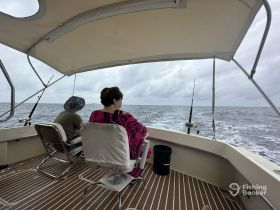 Two guests relax on a fishing boat, enjoying the ocean view while waiting for a catch — a perfect day for fishing enthusiasts.