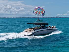 A thrilling scene of a boat cruising through vibrant turquoise waters with a colorful parasail in the background, showcasing the excitement of water sports and adventure on the ocean.