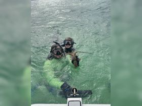 A joyful duo showcases their catch while snorkeling in clear waters, highlighting the excitement of underwater adventures and lobster hunting.