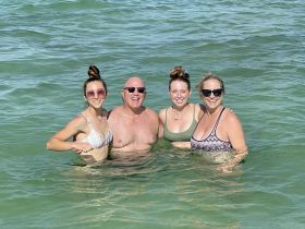 A joyful group of friends enjoys a refreshing swim in clear waters, capturing the essence of fun and relaxation during their beach outing.
