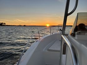 A serene view of a boat at sunset, capturing the tranquil waters and the beautiful horizon — perfect for evening cruises.