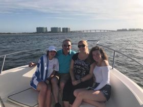 A cheerful group of family members enjoys a sunny day on the boat, capturing memorable moments together against a scenic waterfront backdrop.