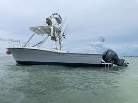 A side view of a fishing boat anchored in calm waters, showcasing its structure and fishing gear — perfect for a day out on the water.