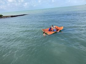 A fun group enjoys a sunny day on a floating mat in the water, showcasing the perfect blend of relaxation and adventure during their boating experience.