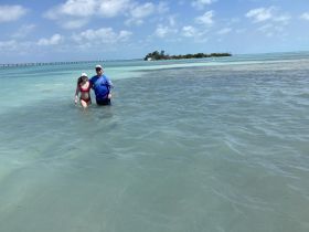 A couple enjoys a refreshing swim in shallow waters, capturing the essence of a perfect beach day at a sandbar.