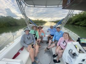 A cheerful group of friends relaxes on a boat surrounded by lush mangroves, enjoying a scenic outing on the water.